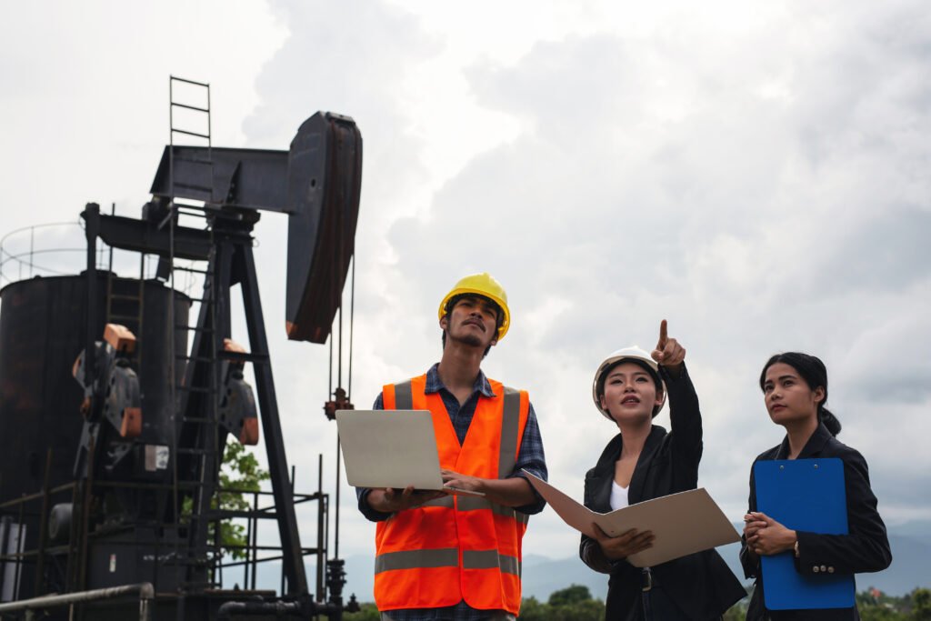 the engineering team stands beside working oil pumps with a sky